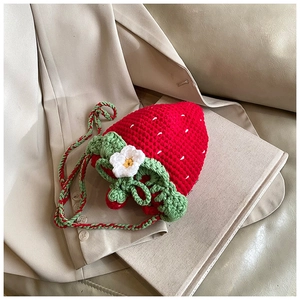 Detail of a handmade crochet strawberry shoulder bag with a white flower on a blazer