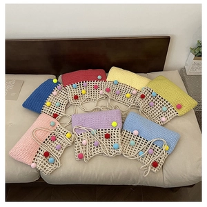 Detailed texture of colorful handmade crochet shoulder bags with decorative soft pom poms