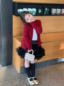 Fillette portant un mini sac à main blanc en cuir avec cardigan rouge et jupe en tutu