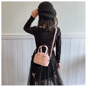 Pink mini shell-shaped bag for kids featuring lychee pattern leather and adjustable strap