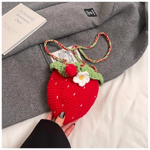 Close-up of handmade crochet strawberry shoulder bag with green leaf and flower detail