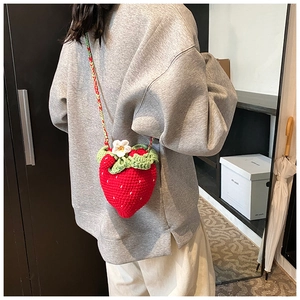 Macro view of a handmade crochet strawberry crossbody bag showing detailed knit texture
