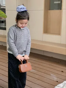 Photo de rue d'un enfant portant un cardigan en maille et un mini sac carré marron