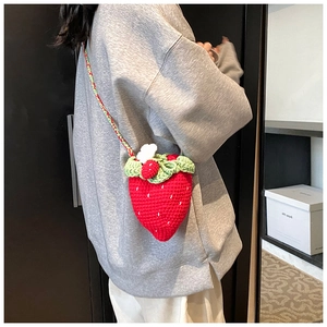 Detailed shot showing the handmade crochet strawberry shoulder bag worn on the side