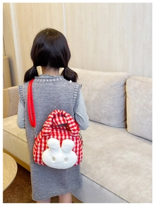 Detail of red checkered plush kid bag with cute rabbit head and metallic strap clips