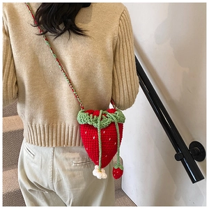 Detailed macro view of handmade crochet strawberry bag with green leaves and white flowers