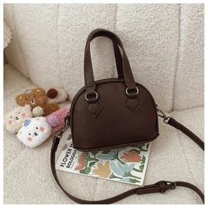 Detail of dark brown mini shell bag showing lychee grain texture and metal hardware