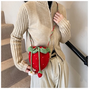 Detail of handmade strawberry crochet bag with 3D leaf and floral charm accents