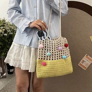 Handmade crochet tote bag with beige mesh, yellow base and colorful pom-poms decor