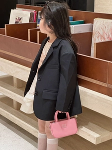 Détail d'un mini sac à main carré rose assorti à un blazer noir surdimensionné pour enfant