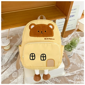 Detail of yellow toddler backpack featuring a plush bear and creative house-shaped front pocket