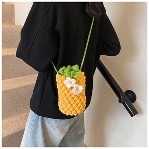 Détail d'un sac à bandoulière ananas crocheté à la main avec tricot jaune et feuilles vertes