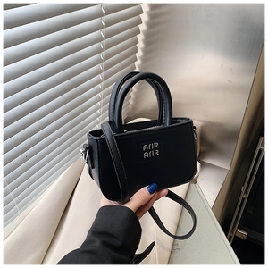 Détail du mini sac carré noir avec logo en métal argenté et doubles poignées hautes