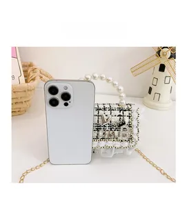 Mini tweed crossbody bag with pearl handle and chain next to iPhone for size comparison