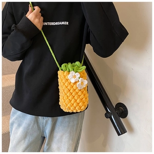 Détail d'un sac ananas au crochet jaune fait main avec feuilles vertes et fleurs