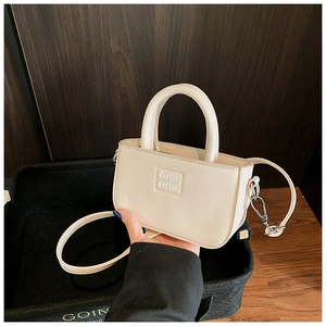 Détail du mini sac carré beige avec doubles poignées et logo Amir sur cuir PU lisse