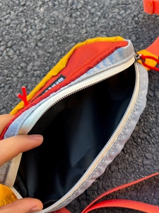 Détail du sac bandoulière multicolore avec fermeture éclair et sangle orange vive