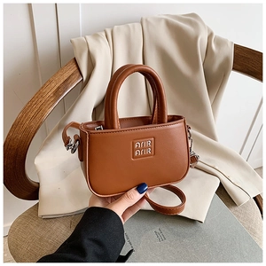 Gros plan du mini sac à main marron caramel avec poignées et logo métallique