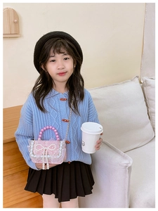 Pink pearl crossbody bag with bow detail styled on a young girl's autumn outfit