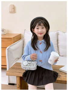Detail of a white woven child bag with pearl handle and floral decoration on girl outfits