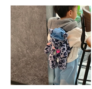 Detail of plush bear backpack featuring purple leopard print and denim cap on a child