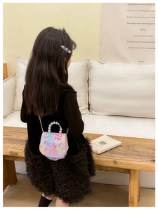 Detail of girl's crossbody bag with pearl handle, sequins, and lace in gradient pink