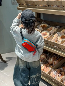 Gros plan d'un sac bandoulière enfant en nylon bicolore avec tenue urbaine tendance