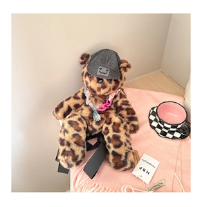 Detail of plush leopard bear pendant with denim cap and pink chain on pink scarf