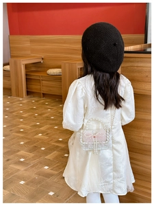 Detail of girls' lace crossbody bag with pearl handle and pink mesh bow decoration