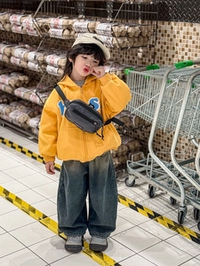 Gros plan sur un sac de poitrine gris pour enfant avec sweat à capuche jaune et un jean