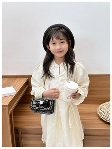 Detail of a girl's cream-colored dress with jacquard texture and Chinese frog buttons