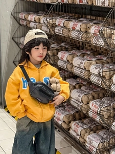 Détail d'un sweat à capuche jaune pour enfant avec motif et petit sac bandoulière noir