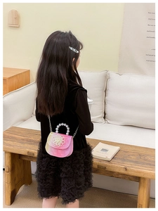 Detail of child glitter handbag featuring large 3D flower pearl handle and metal chain