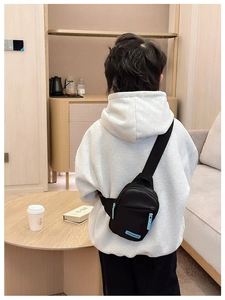 Rear view of kid's black crossbody chest bag with blue zipper detail and nylon strap