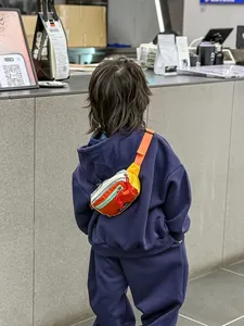 Vue arrière d'un sac bandoulière enfant en nylon orange et jaune pour extérieur