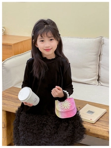 Girl in black mesh skirt holding pink floral pearl bag in cozy indoor setting