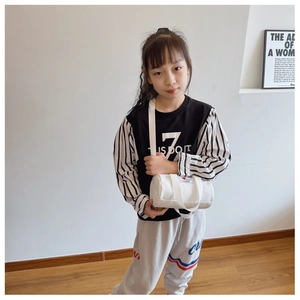 Girl wearing a white canvas cylinder crossbody bag featuring a fashion heart patch
