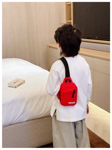 Detail of red canvas kids chest bag with adjustable strap and brand label on back