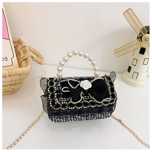 Detail of tweed kids bag with black bow, white rose, pearl handle and gold chain strap