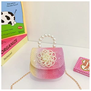 Detail of pink and yellow gradient children handbag with pearl handle and floral accent