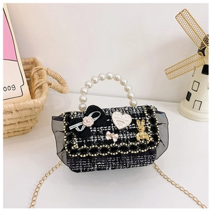 Detail of tweed crossbody bag featuring pearl handle, bow, and gold bunny pendant charms