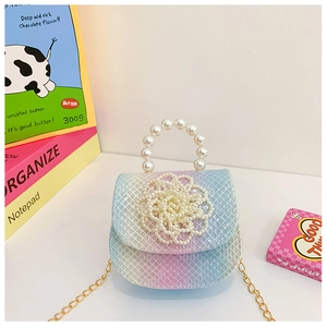 Close-up of girls' mini handbag featuring pearl handle and woven flower on gradient PU