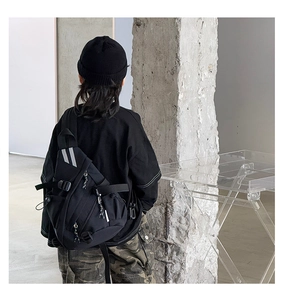 Detail of black tactical nylon crossbody bag featuring reflective strips and adjustable straps
