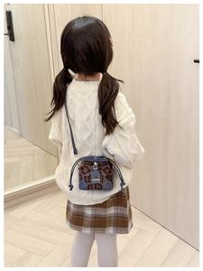 Detail of child leopard print bucket bag with navy leather trim and gold fashion tag