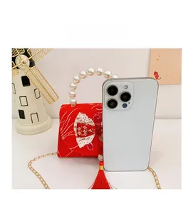 Detailed size comparison of red satin girl purse with pearl handle and a smartphone