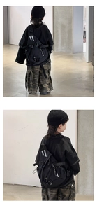 Detail of black tactical nylon kids crossbody bag with reflective stripes and buckle detail
