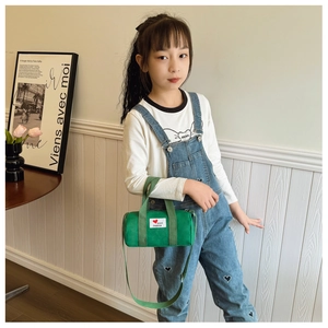 Detail of green canvas bucket bag for kids with fashion patch and shoulder strap
