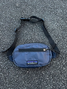 Détail d'un sac de poitrine enfant en nylon ripstop bleu foncé sur fond d'asphalte