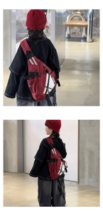 Detail of red and white kid's crossbody bag featuring a fashion label and buckle strap