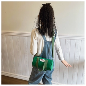 Green canvas bucket bag for kids with red heart patch shown in a back-view model pose